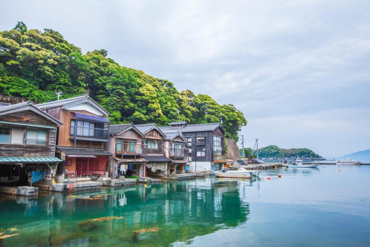 伊根位於京都北部丹後半島,是一座寧靜純樸的海濱漁村,其傳統建築「舟屋」是一大特色。一棟棟貼海而建的舟屋,一樓作為船庫,二樓為居住空間,展現伊根人與海共生的智慧。漫步在舟屋群之間的小徑,彷彿穿梭時光,感受濃厚的漁村人情與自然氣息,讓人沉浸在悠閒緩慢的海岸生活之中。